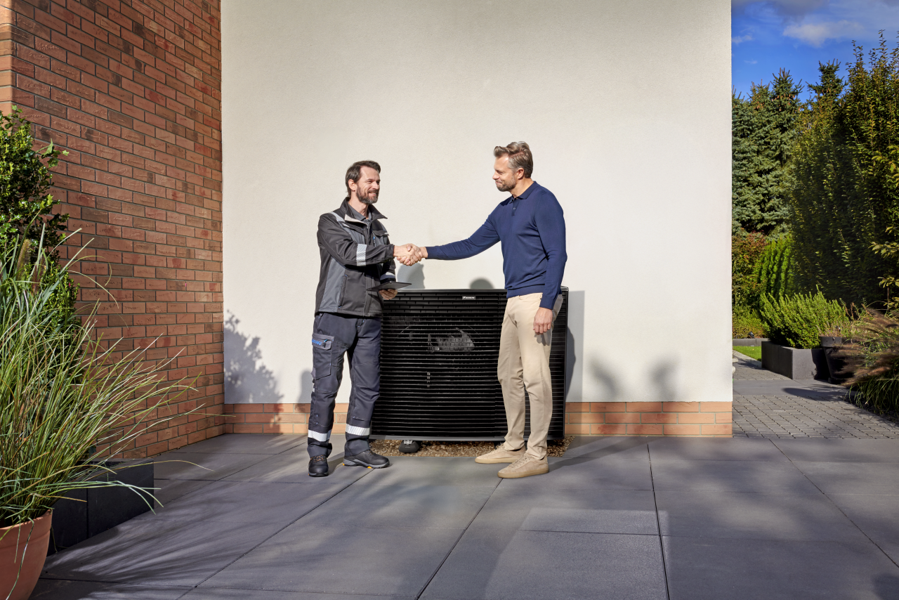 Установник тисне руку клієнту перед зовнішнім блоком Daikin Altherma