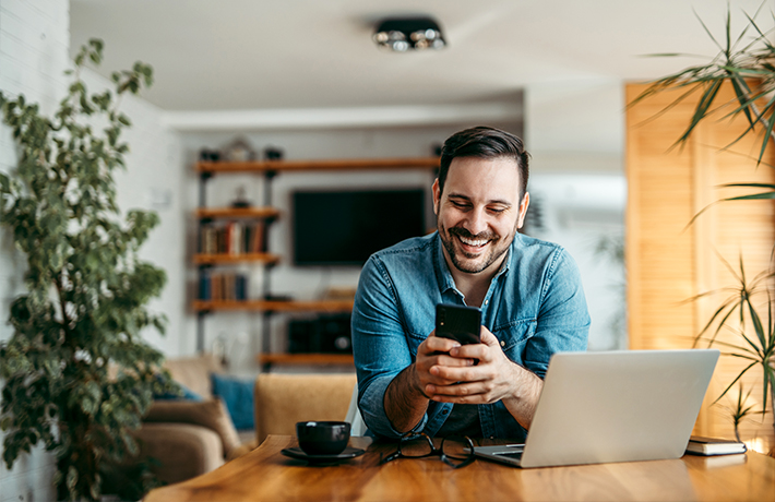 Чоловік дивиться на екран свого мобільного телефону вдома